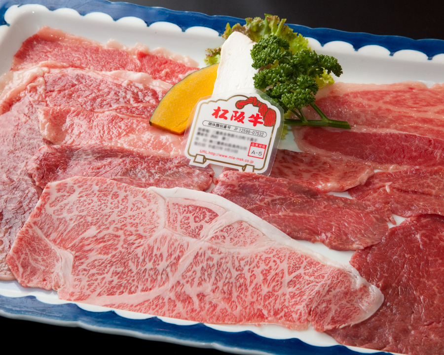艶のある焼肉の盛り合わせを木目のテーブルに美しく並べた近景写真