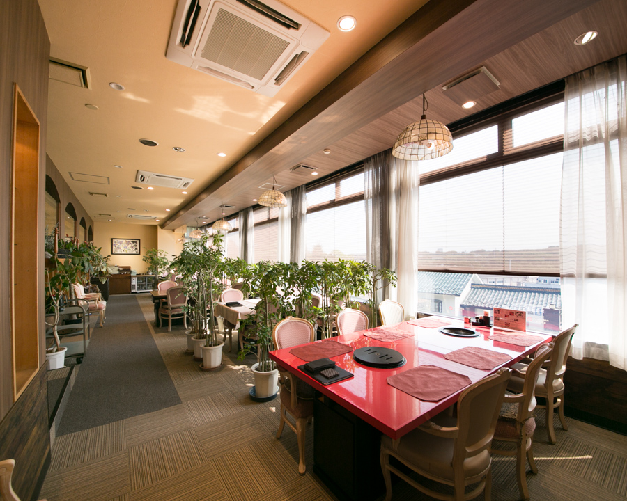 店内の窓から山並みを望みながら食事できる明るいテーブル席の風景