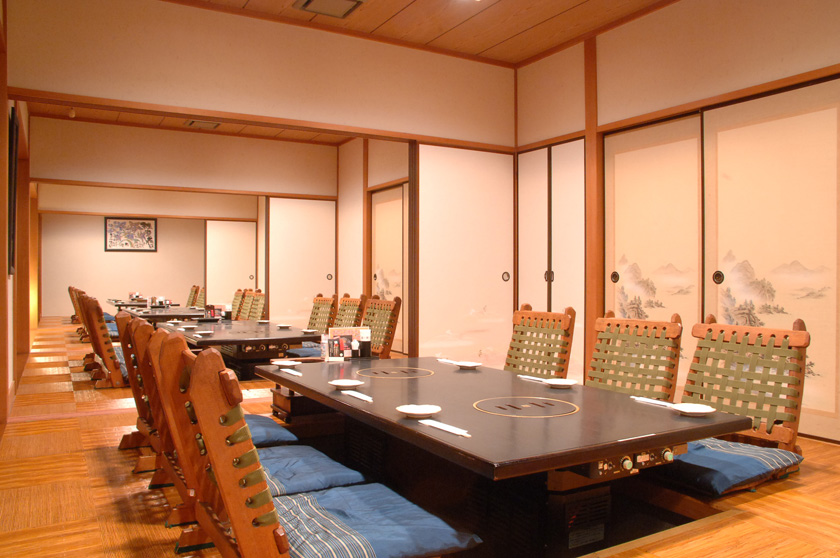 掘込み座敷で足を伸ばしてくつろげる焼肉店の個室空間、木の卓とやわらかな照明