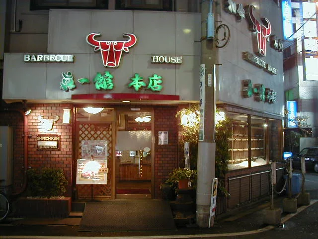 白い湯気がゆるやかに立ちのぼる焼肉テーブルと落ち着いた木目の店内席